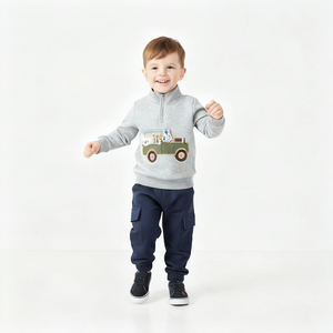 Child wearing a gray sweater with a truck design and navy pants on a white background