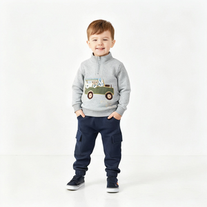 Child wearing a gray sweatshirt with a truck design and navy pants on a white background