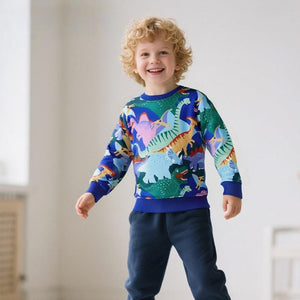 Child wearing a colorful dinosaur sweater in a room with a light background